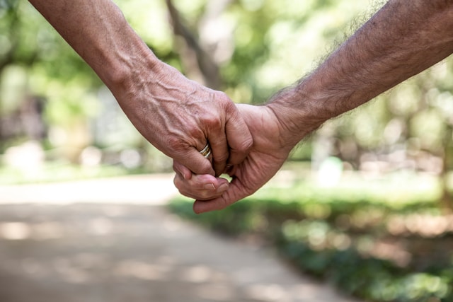 Foto de dos personas cogiéndose de las manos. La foto sólo enfoca las manos con un fondo difuminado de un parque.